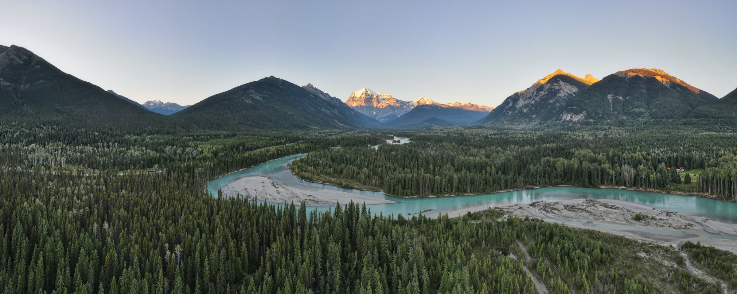Aerial view of a wide glacial river running beneath high snow-capped mountains