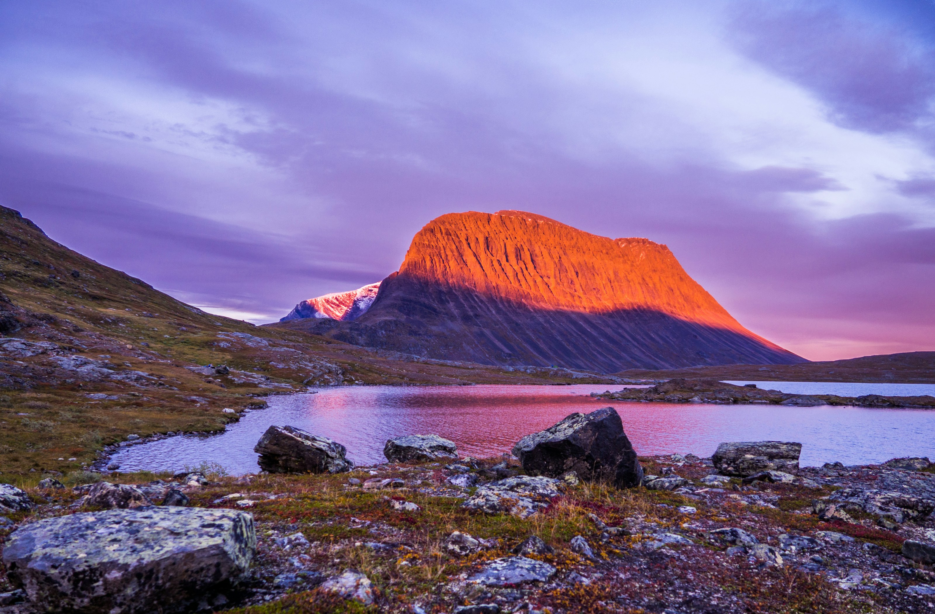 Alpenglow on the massif above Kebnekaise fjällstation, a tarn dark in the foreground
